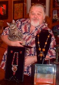 James-Ben Stockton in his Greeneville gallery. Jewelry shown in foreground: On left, the necklace and earring demi-parure (matching set of jewelry) is sterling and copper in a lost-wax cast sterling setting hung from forged sterling and a handmade sterling chain utilizing Native American white-hearts from the late 18th century. On right, a necklace features hand-made copal amber beads and Gold Coast 19th-century trade beads with cast and fabricated sterling beads. 