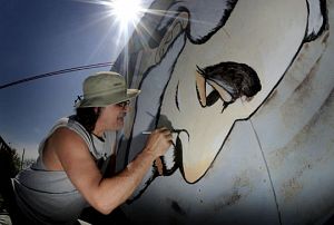 Local muralist D.R. Mullins paints on Robert E. Lee's nose as he restores the landmark motel sign. (Photo by Andre Teague | Bristol Herald Courier.)