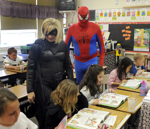 Avoca Elementary School principal Myra Newman, dressed as Batwoman, and program assistant Jeff Mustard, dressed as Spiderman, talk with second-grade students.